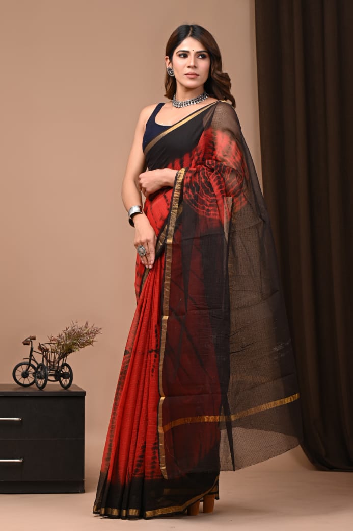 Woman wearing a red and black saree with a brown background