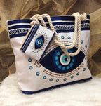 White bag with blue and green eye design and rope handles on a textured surface