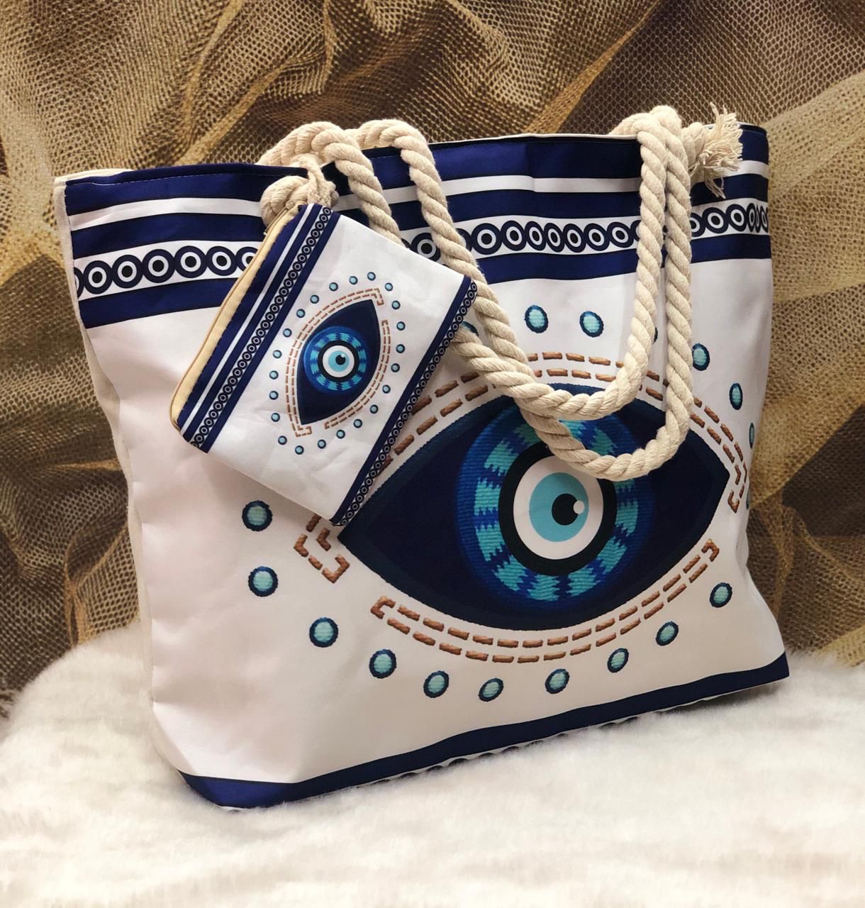 White bag with blue and green eye design and rope handles on a textured surface